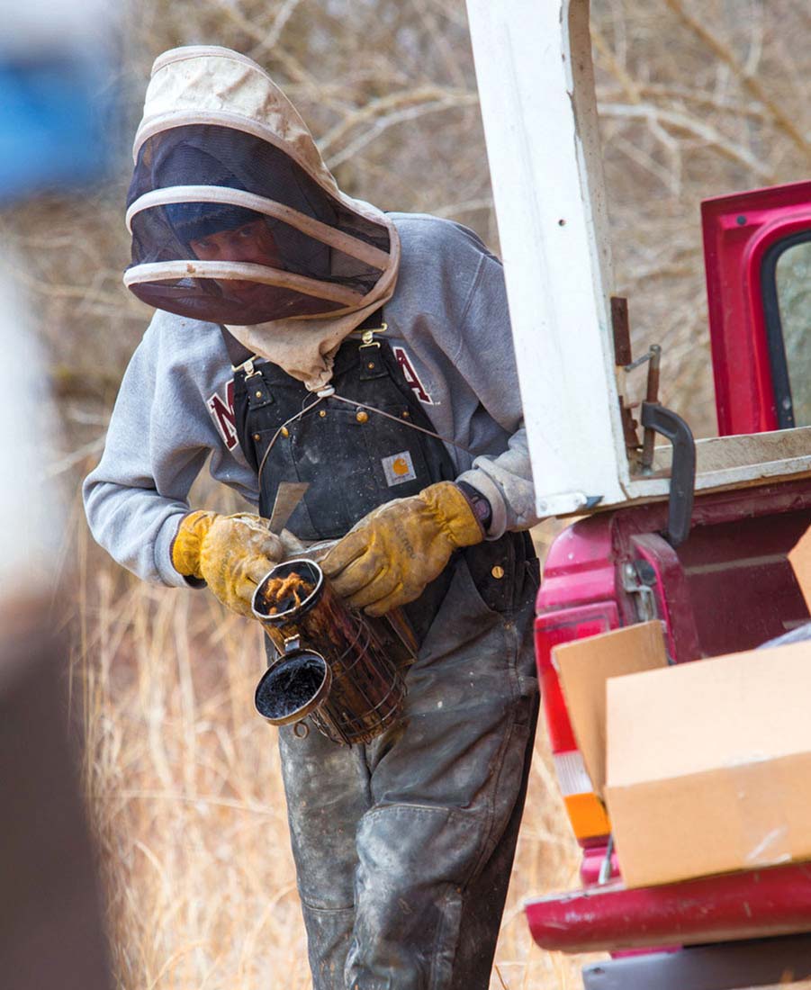 Isaac Barnes tends to bees at Honeyrun Farm. Photo by Edible Columbus.