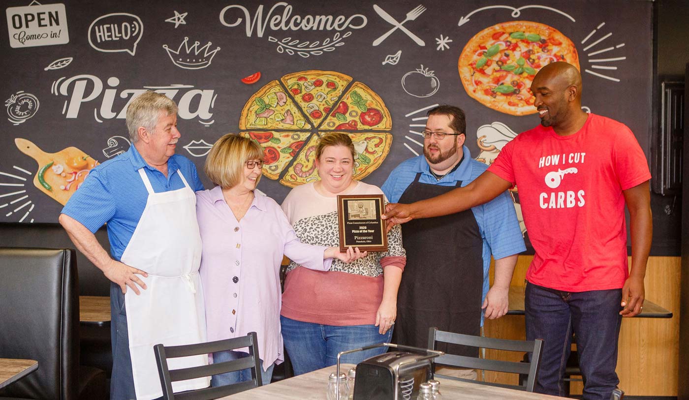 Nakimba Mullins, right, presents the Pizza Connoisseurs' annual award to Pizzaroni's owners, from left: Tony, Valerie, Danielle and Dustin Sabatino.