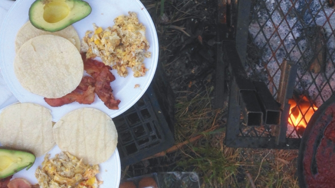 plate of avocado, bacon, tortillas, and eggs at a campsite
