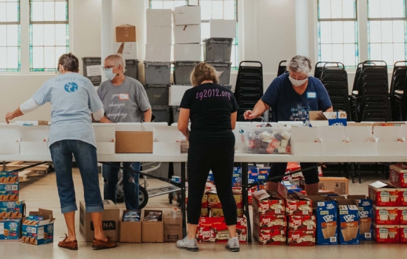 An assembly line fills hundreds of food boxes a week.